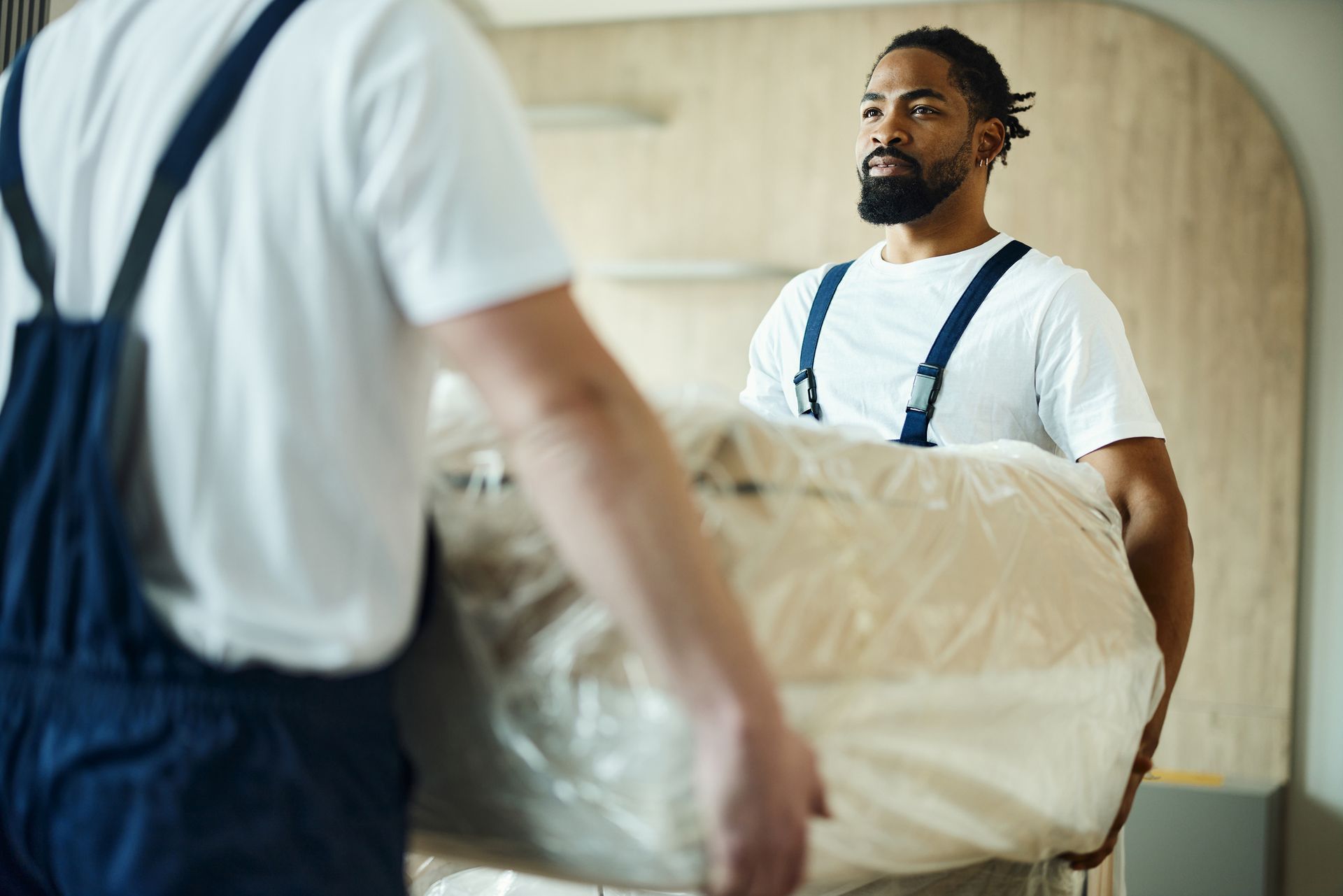 Happy male movers carrying furniture in the apartment