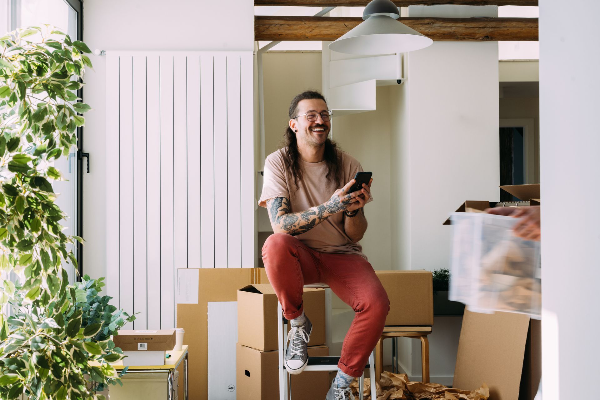 Smiling tattooed man with a phone during moving day