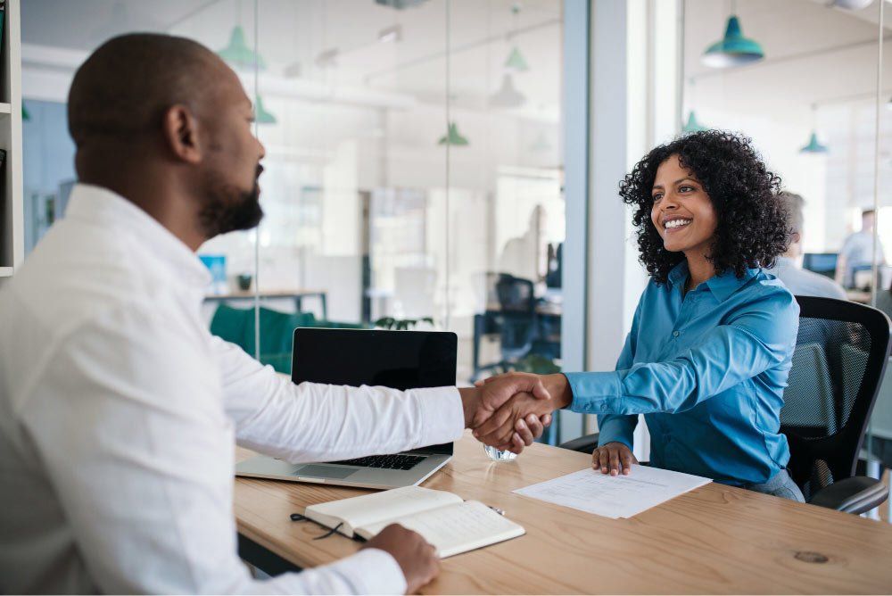 A man and a woman are shaking hands during a job interview.