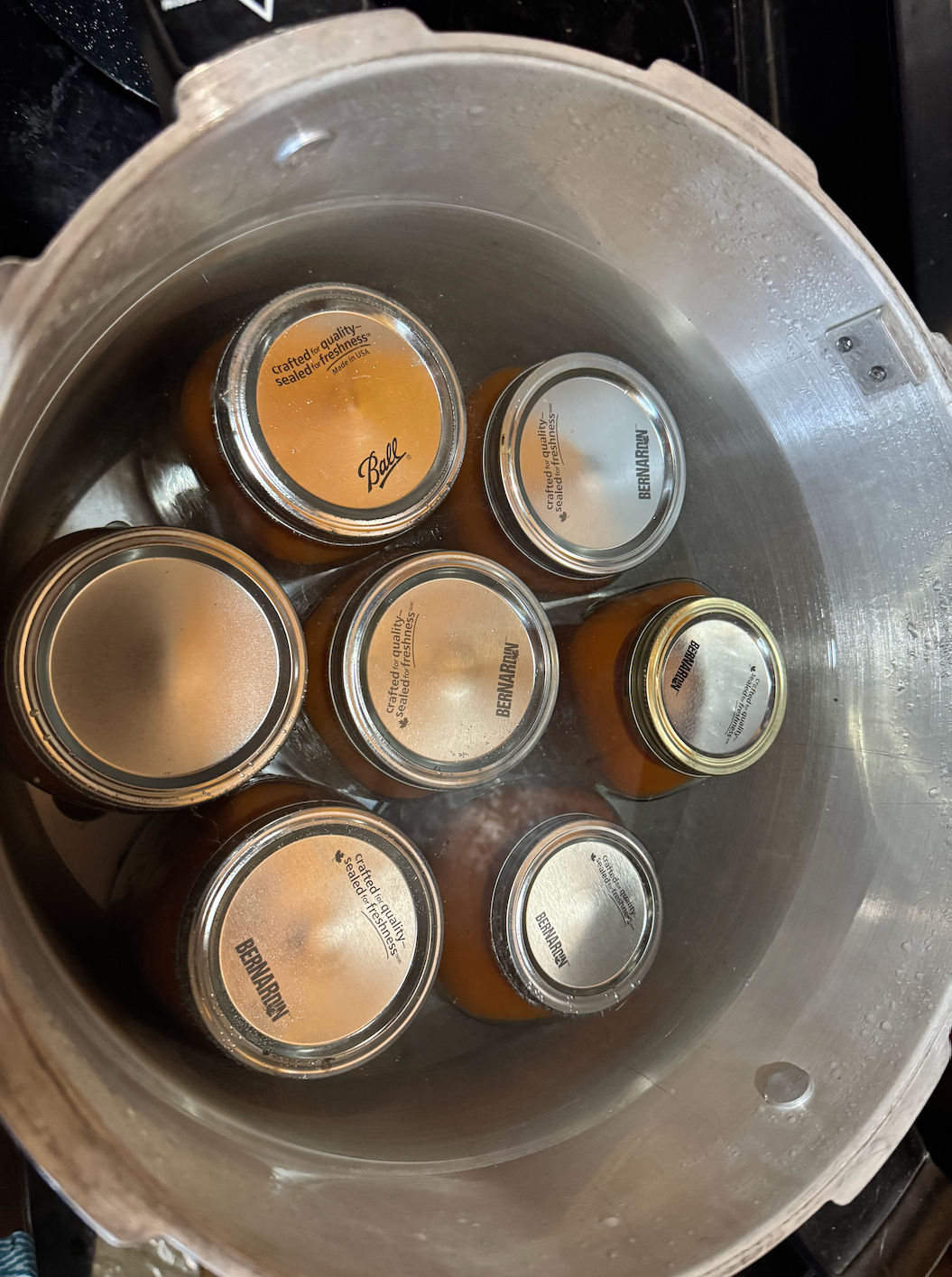 A group of jars are sitting in a pot of water.