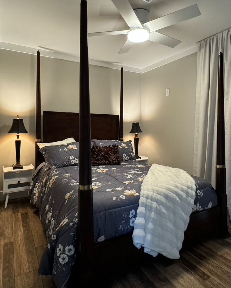 A bedroom with a four poster bed and a ceiling fan