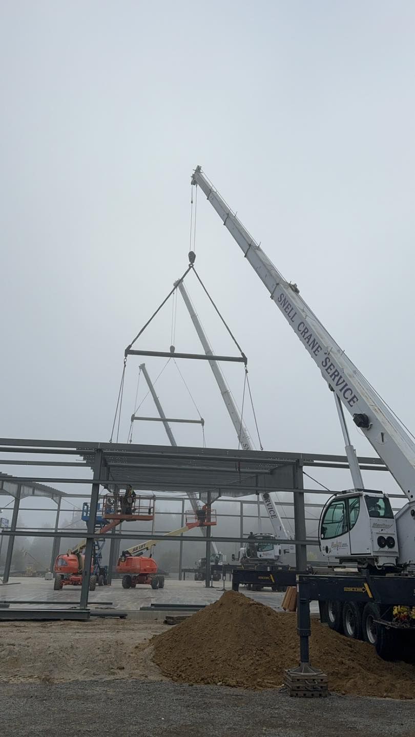 Crane lifting steel beams for a building frame at a construction site under a gray sky