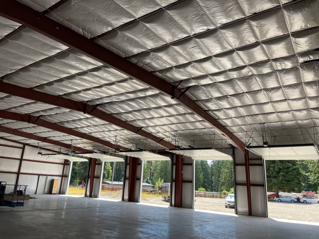 Large open metal warehouse with insulated roof, concrete floor, and wide bays opening to the outside