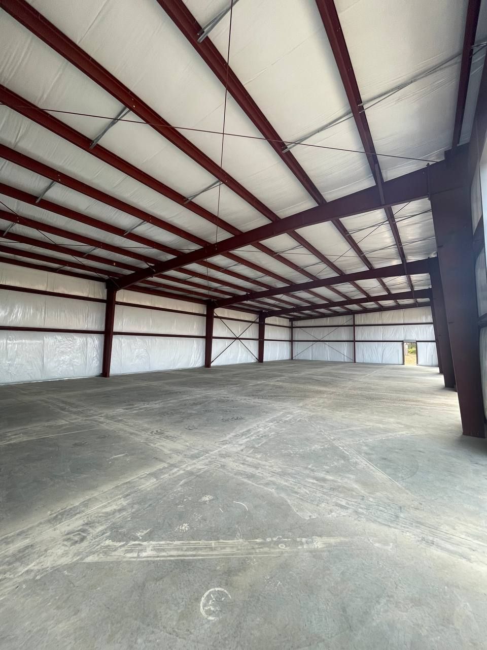 Empty industrial warehouse with steel beams, concrete floor, and white insulated walls