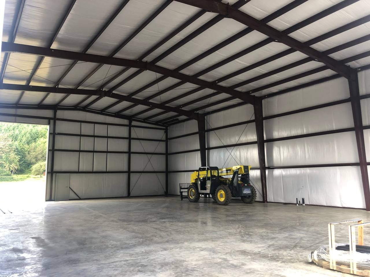 Large empty metal warehouse with a small yellow forklift near the back wall