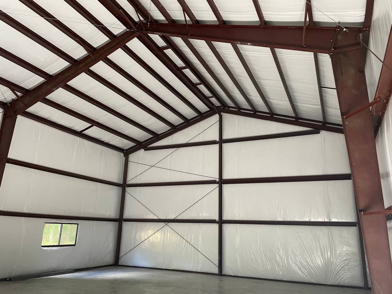 Empty metal-walled warehouse interior with exposed steel beams and a concrete floor