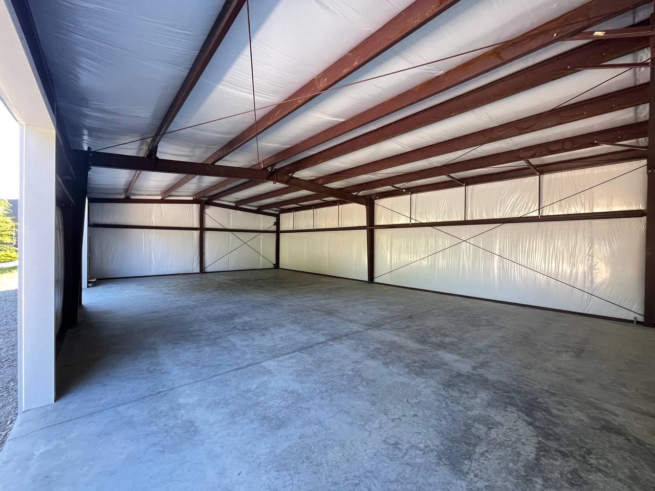 Empty metal-framed warehouse with concrete floor and corrugated roof interior