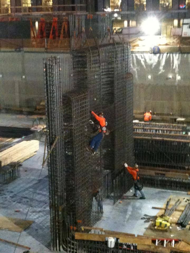 Construction workers on a rebar column at a building site at night