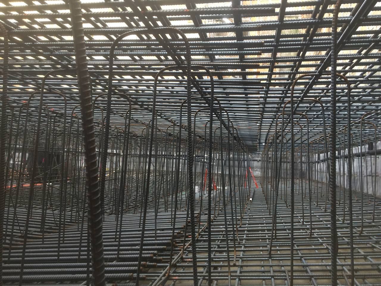 Dense grid of metal scaffolding inside an unfinished building, seen from ground level