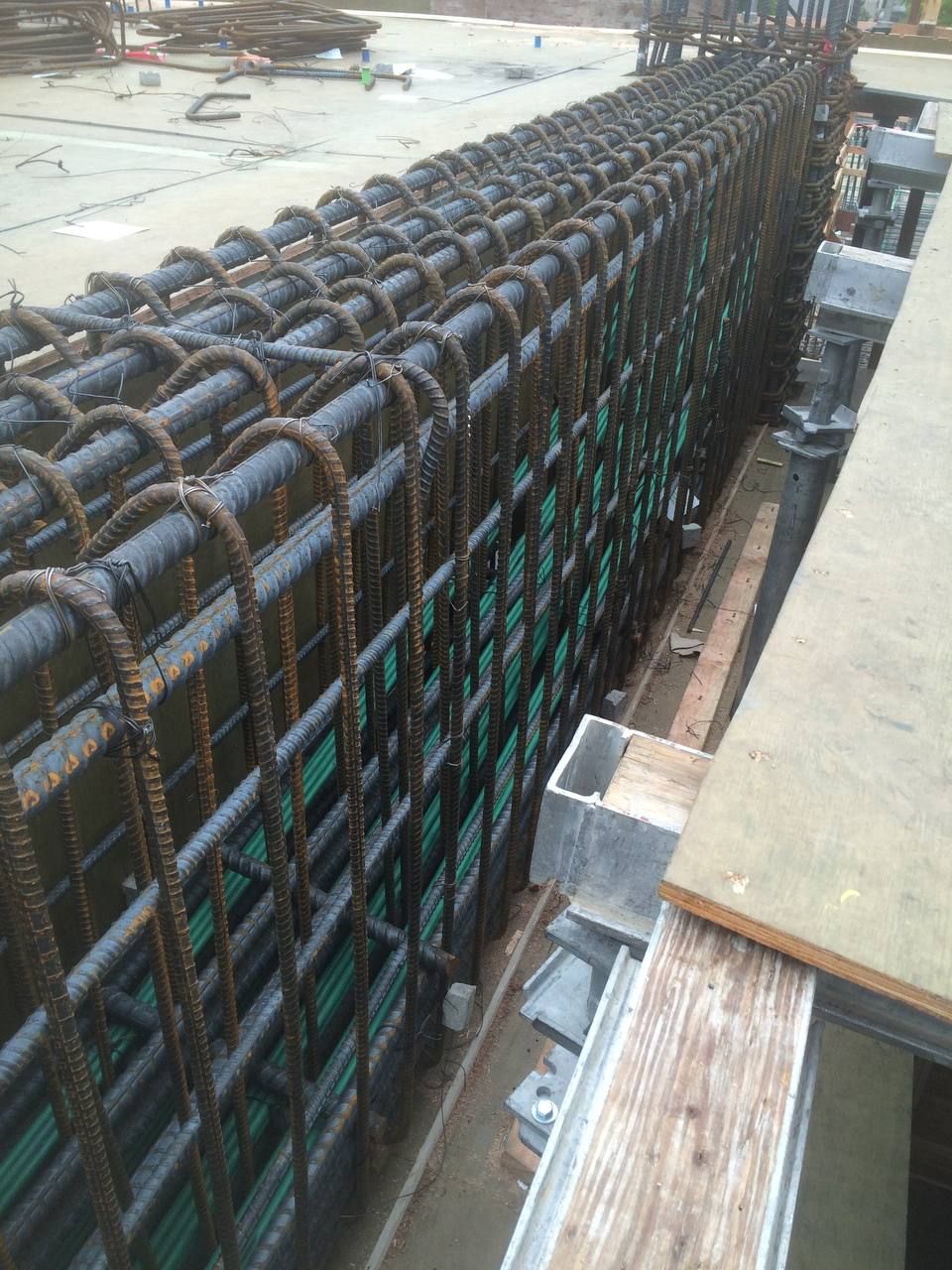 Steel rebar cage on a construction site, viewed along a narrow walkway.