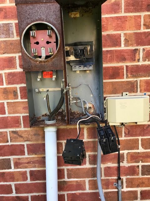 An electrical box is sitting on a brick wall.