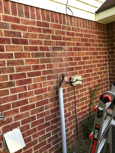 A ladder is sitting on the side of a brick wall.