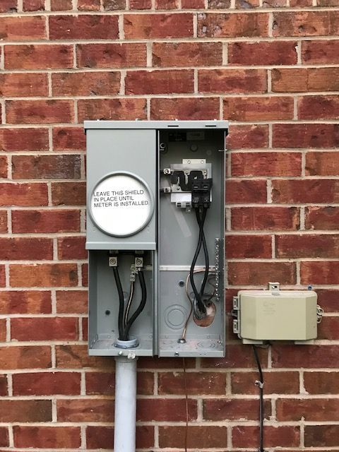 A brick wall with a electrical box attached to it.