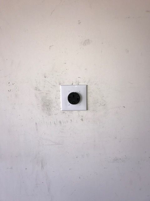 A white wall with a black button on it.