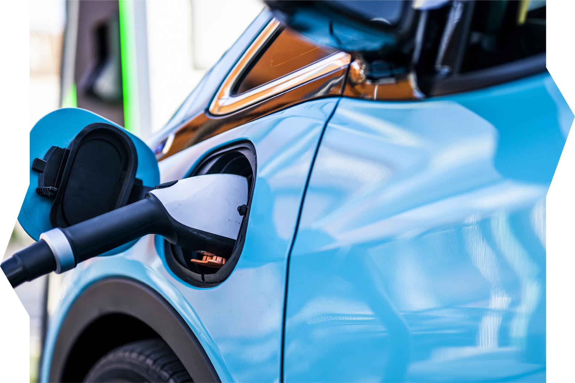 Blue electric car being charged at a charging station with a charging cable plugged in.