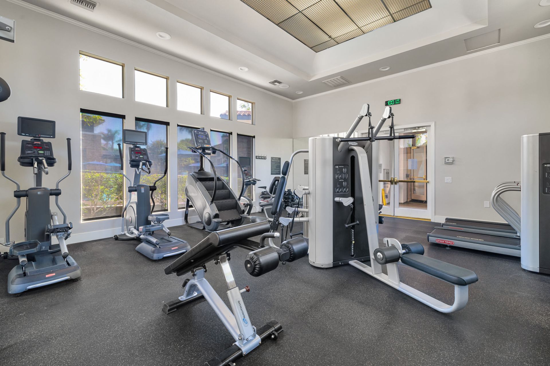Community gym interior with treadmills, ellipticals, and a weight machine at Alize Apartment Homes in Aliso Viejo, CA.