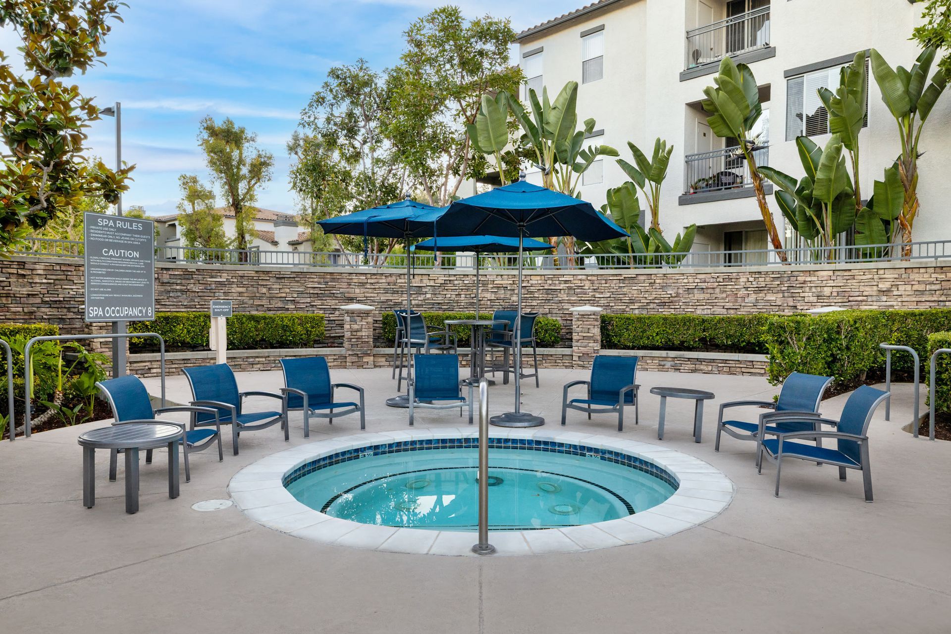 Outdoor pool area with blue lounge chairs and umbrellas at Alize Apartment Homes in Aliso Viejo, CA.