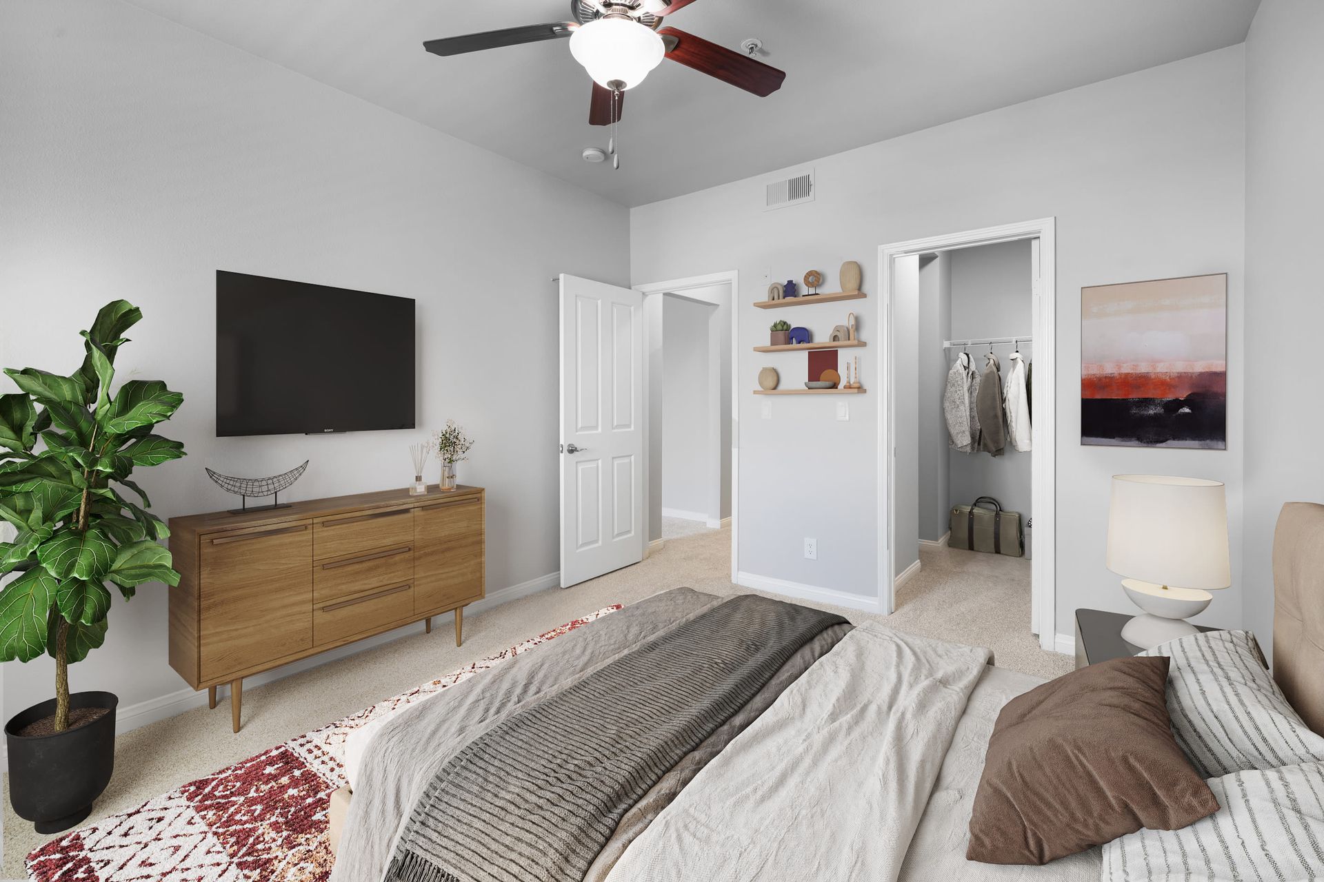 Bedroom in a modern apartment with bed, dresser, TV, and open closet at Alize Apartment Homes in Aliso Viejo, CA.