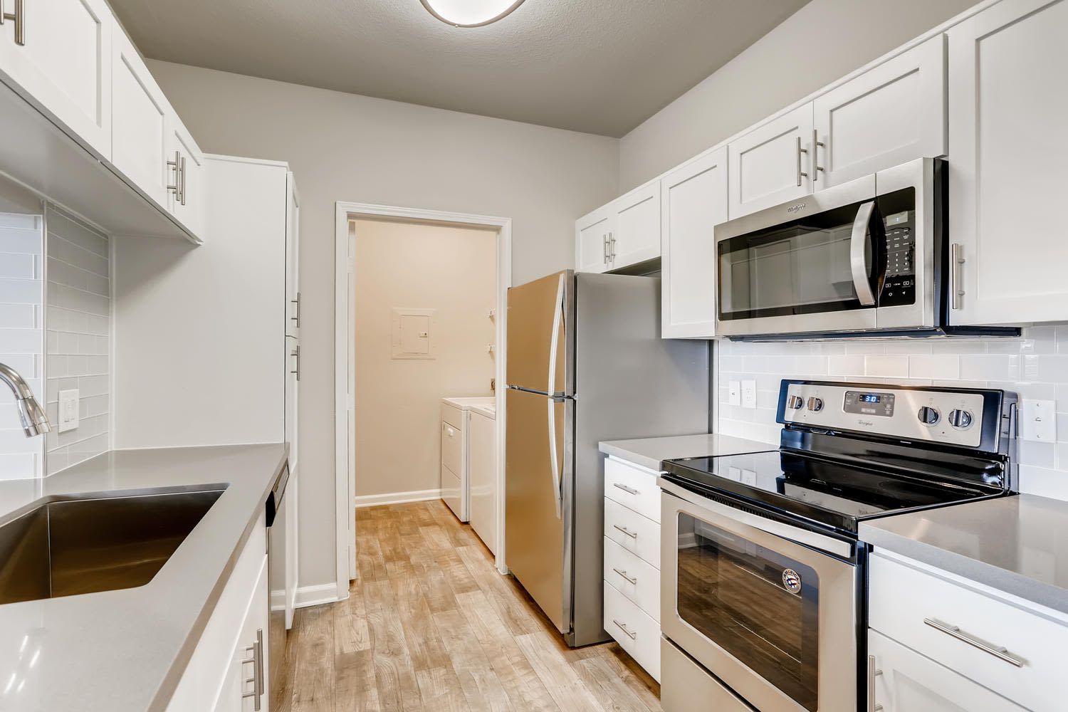 Modern apartment kitchen with white cabinets, grey countertops, and stainless steel appliances at Alize Apartment Homes in Aliso Viejo, CA.