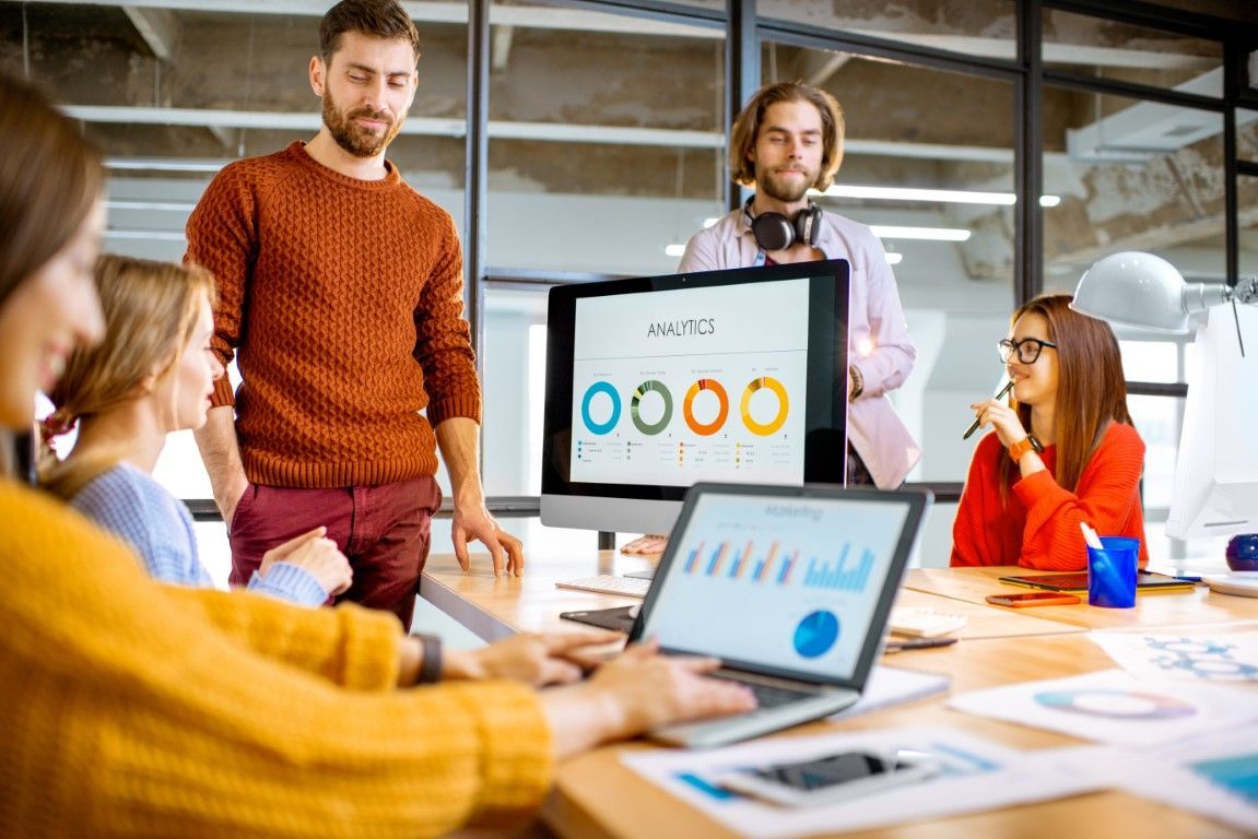 Team in modern office, looking at computer screens, discussing data visualizations.