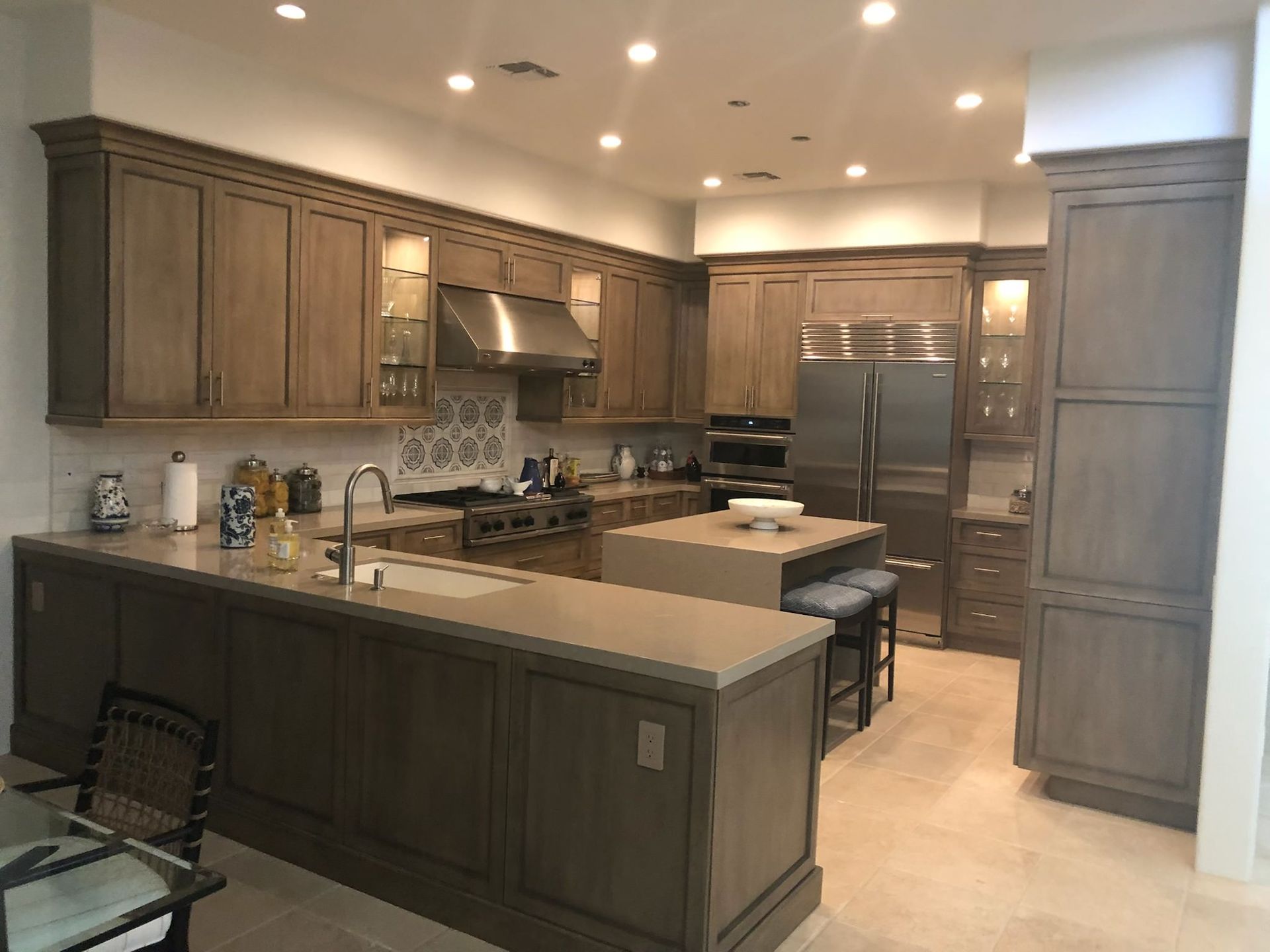 A kitchen with greyish brown cabinets, stainless steel appliances, and a central island.