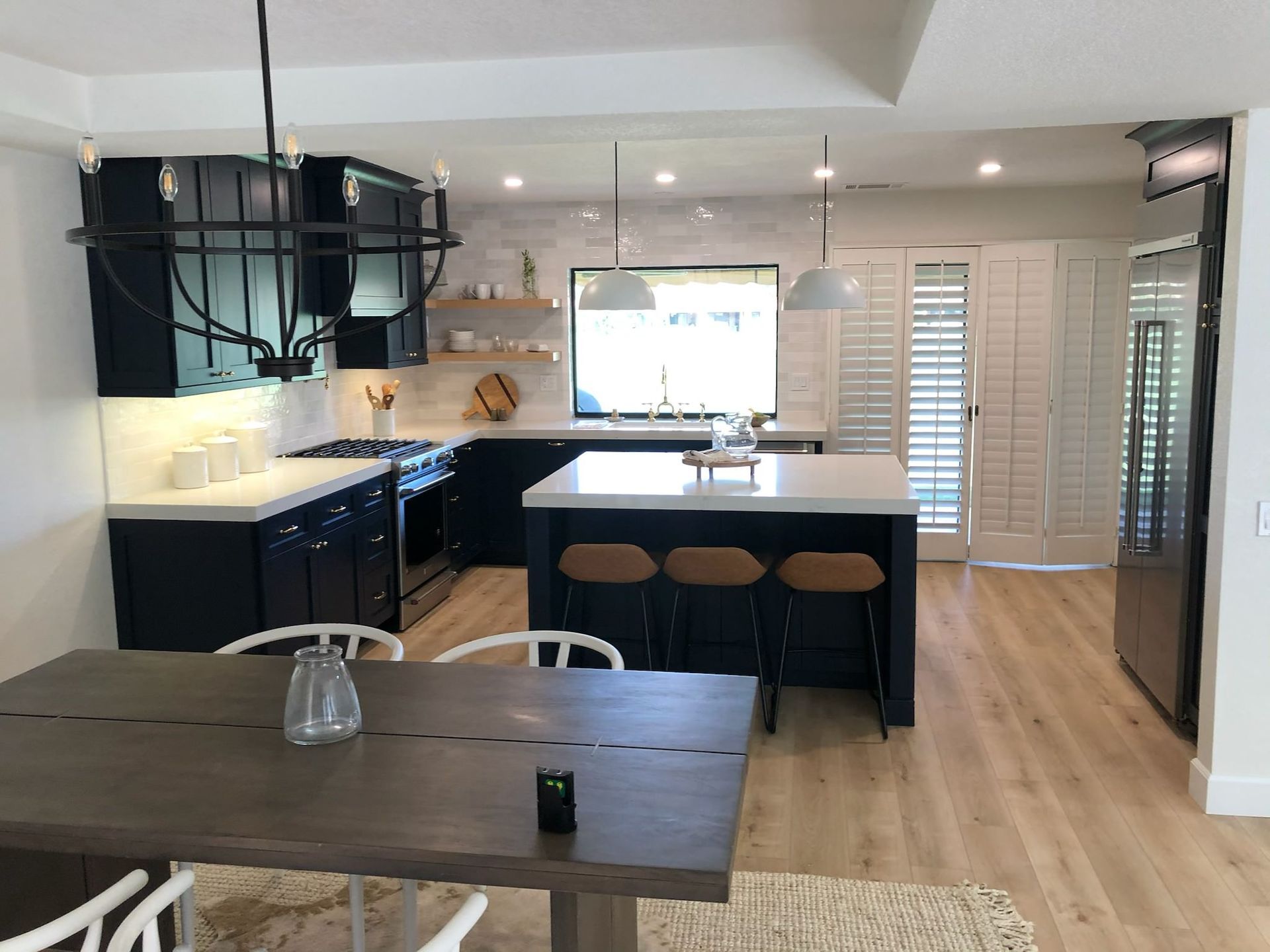 Modern navy kitchen with white countertops, island with bar stools, dining table.