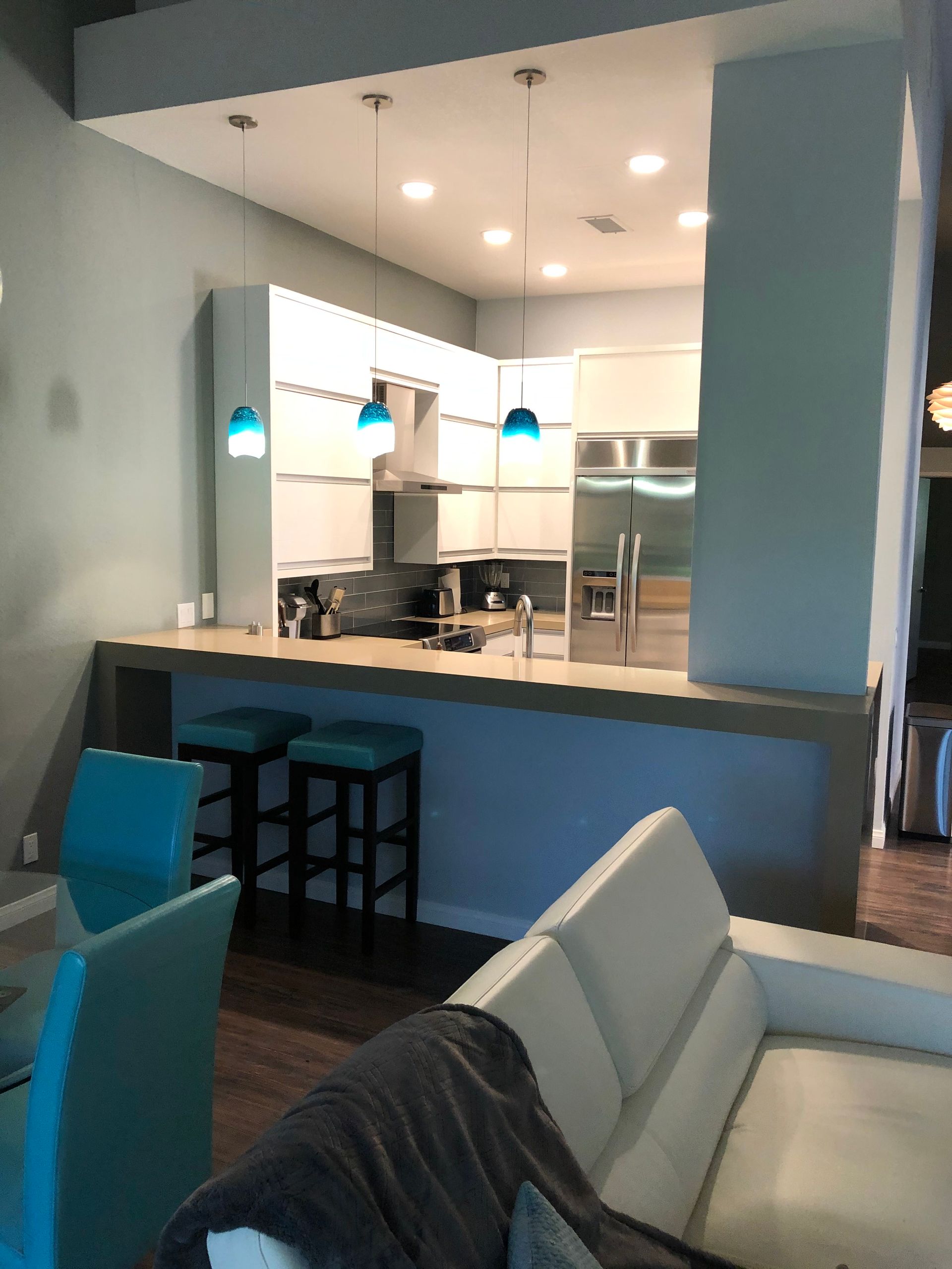 Modern kitchen with teal accents, built-in cabinets, and bar seating.