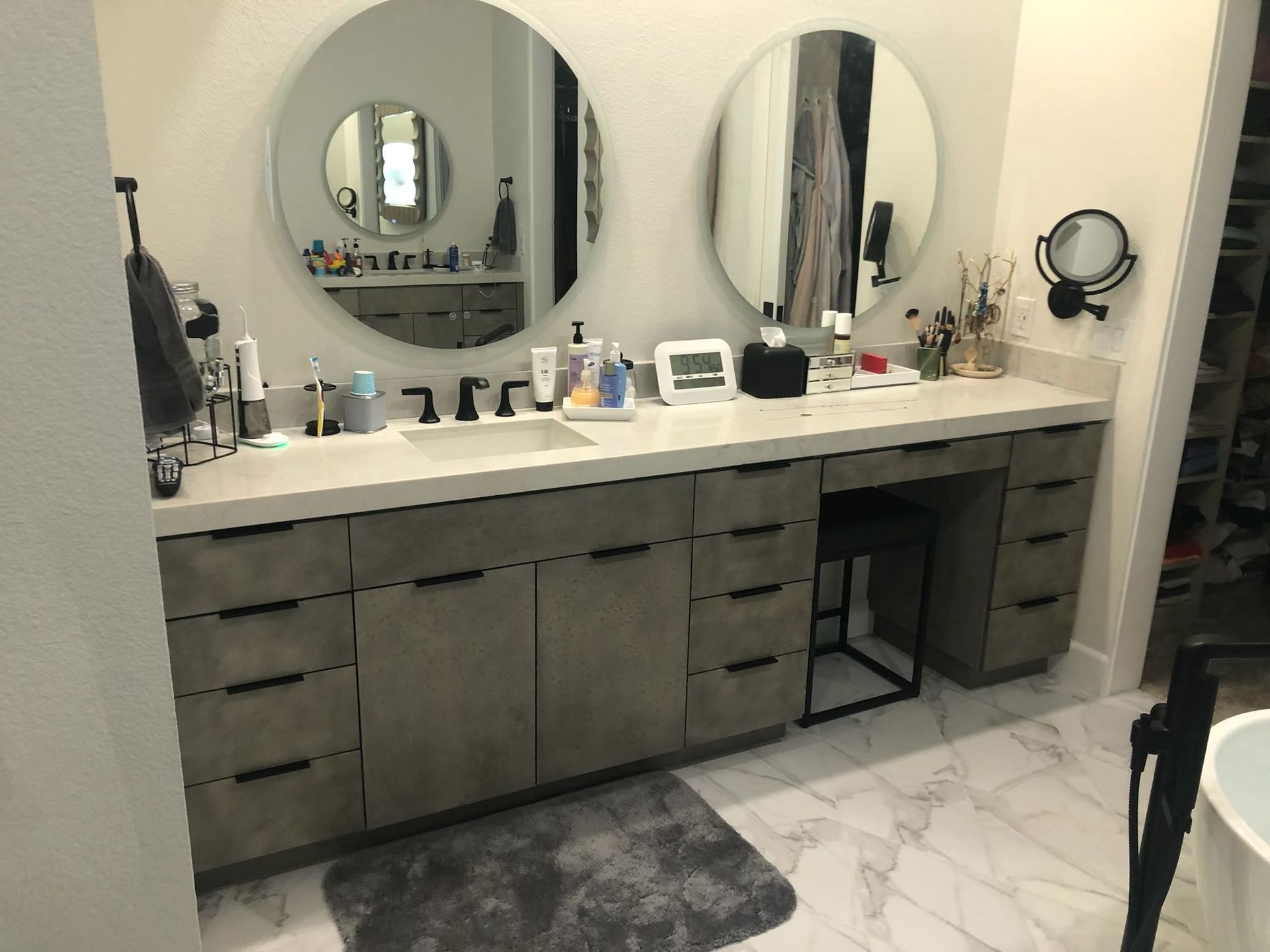 Bathroom vanity with two circular mirrors, drawers, and a stool.