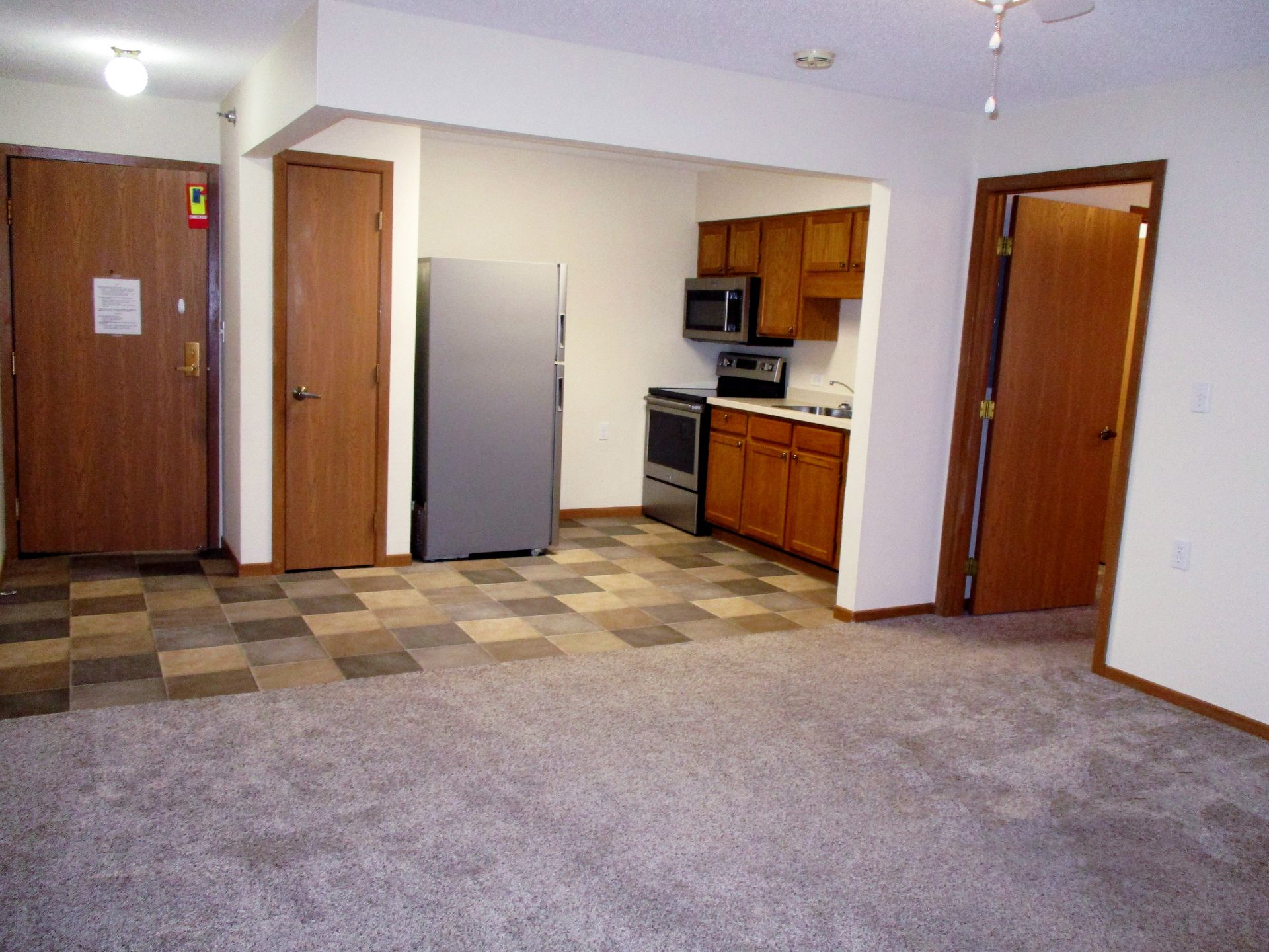 An empty apartment with a kitchen and a refrigerator