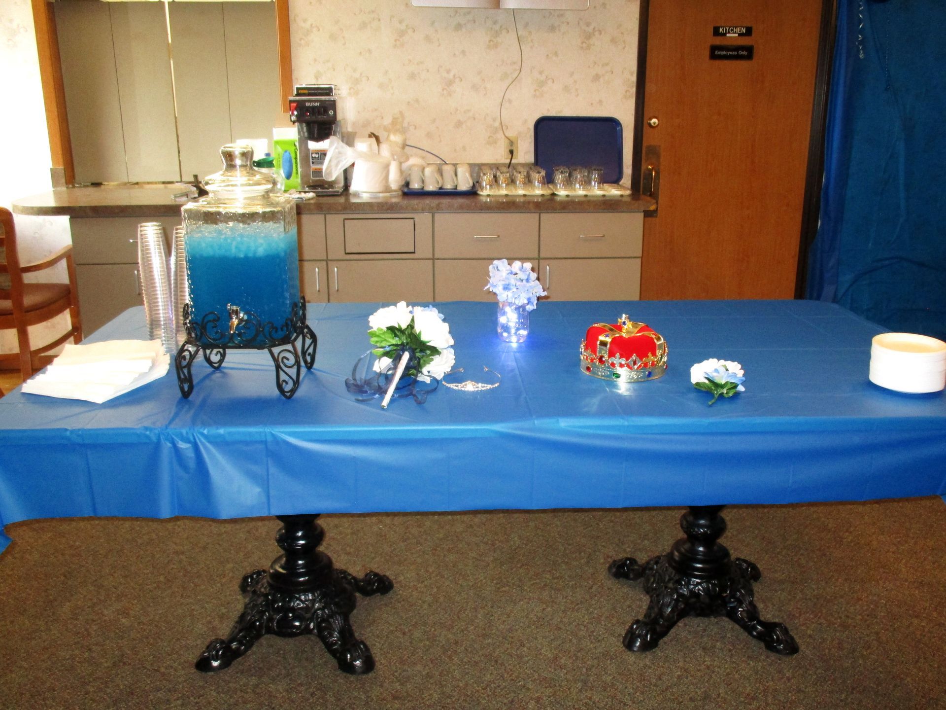 A table with a blue table cloth and a blue drink dispenser