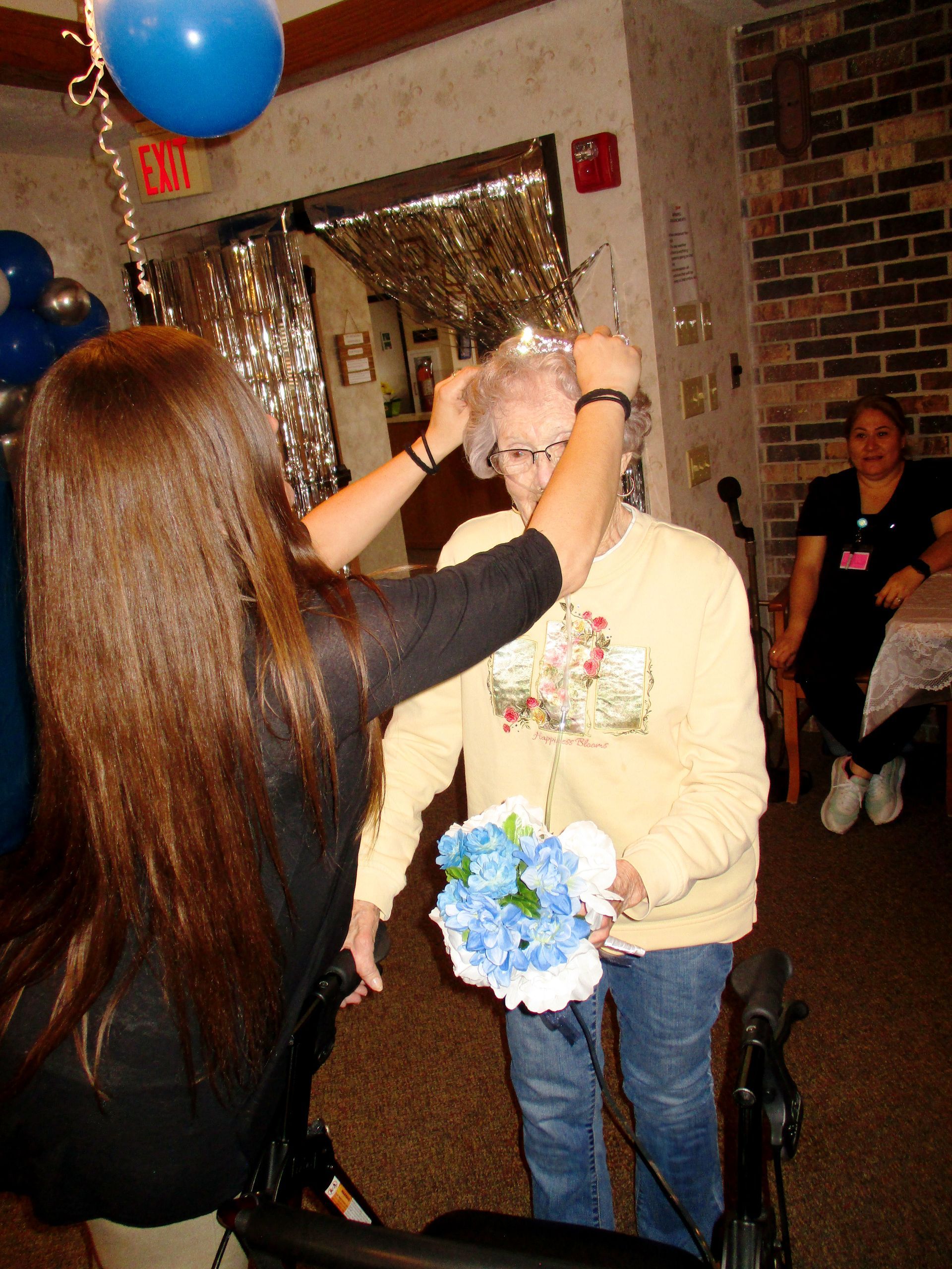 A woman is putting a crown on an older woman 's head