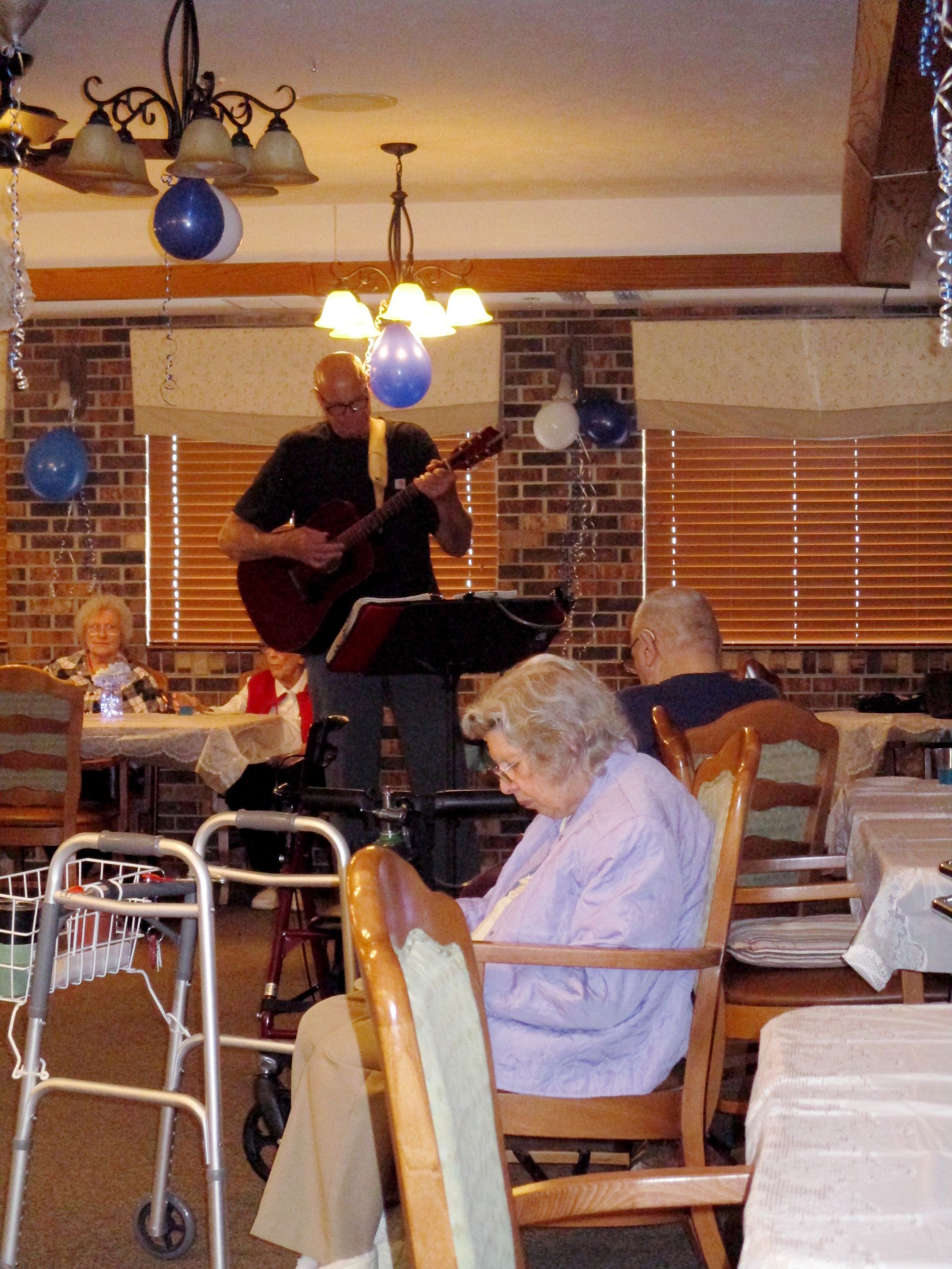 An woman sits in a chair while a man plays a guitar