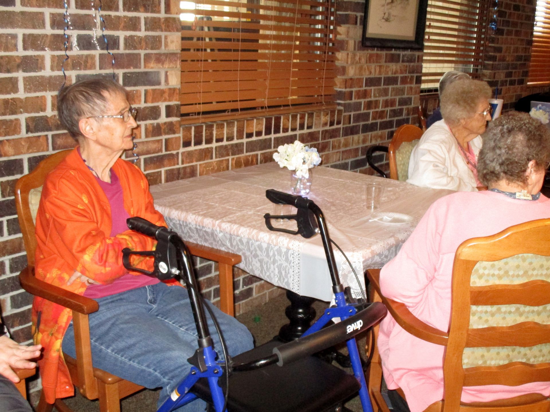A woman with a walker sits at a table with other people