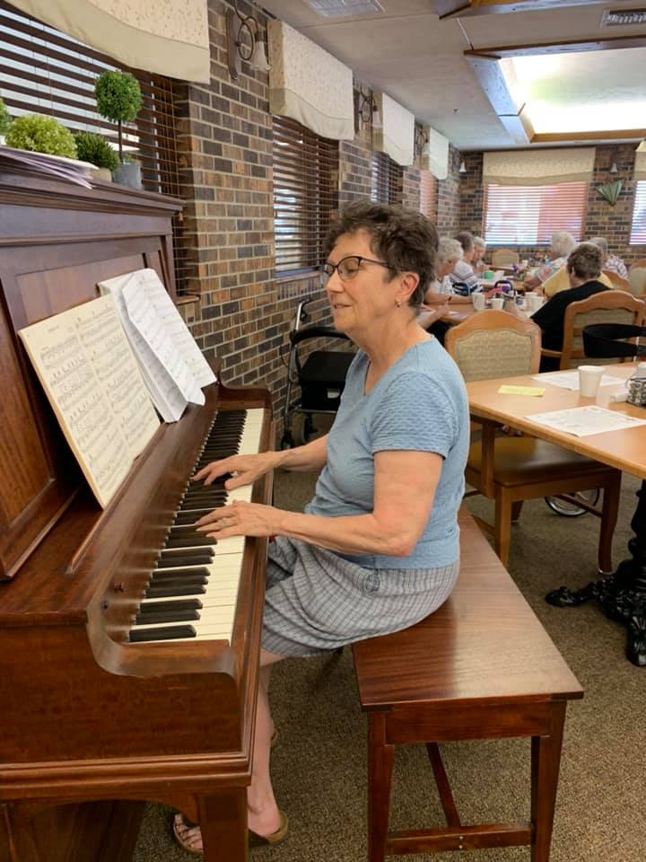 A woman is sitting on a bench playing a piano in a room.