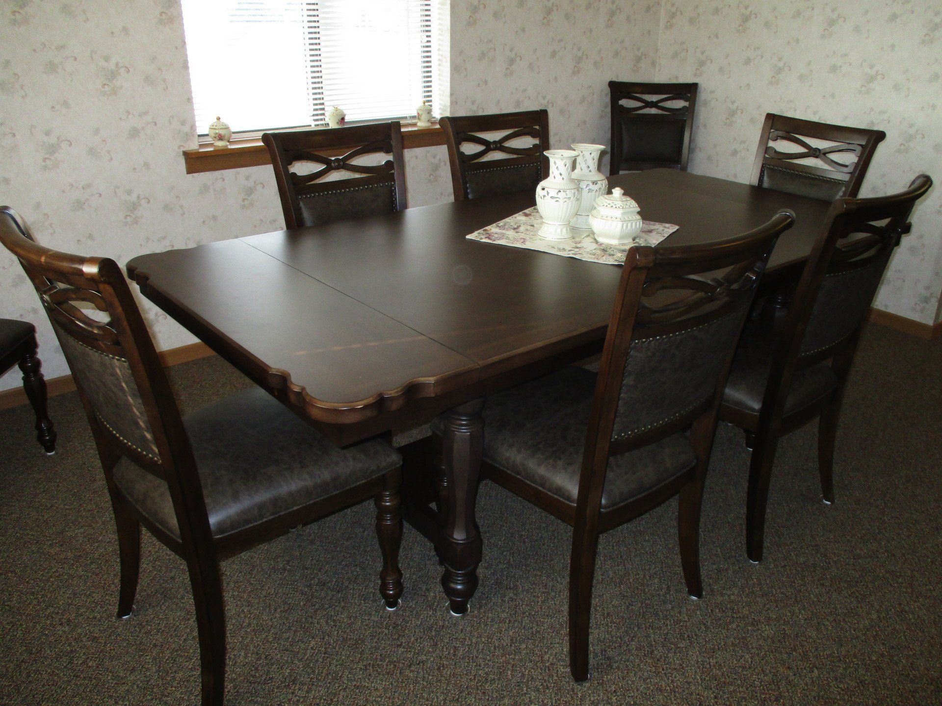 A dining room table and chairs in front of a window