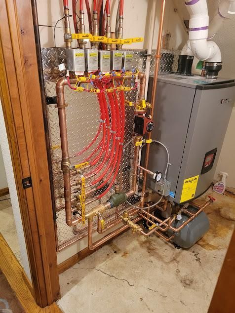 Copper pipes and red PEX tubing connected to a boiler.