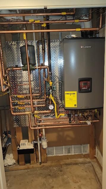 Copper pipes and a gray water heater in a utility closet.