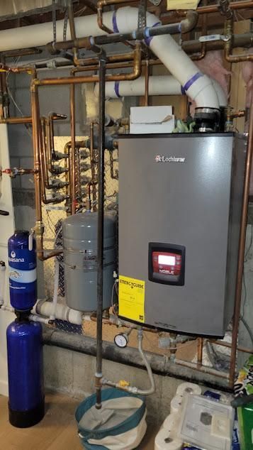 A gas boiler with pipes, a water filter, and other equipment in a basement setting.