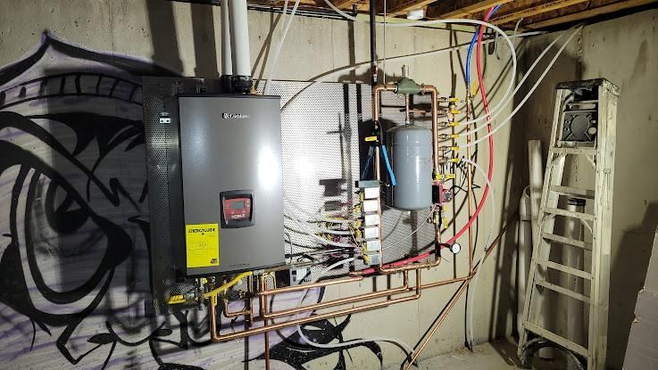 Tankless water heater and connected plumbing on a basement wall. Graffiti art is on the adjacent wall.