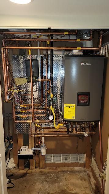 Copper pipes and a gray boiler in a utility room. Yellow gas valves, silver insulation.