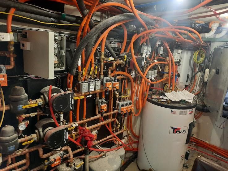 Complex system of orange pipes and machinery in a utility room.