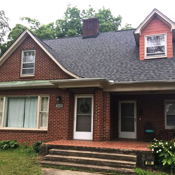 A brick house with a roof that has a chimney on it