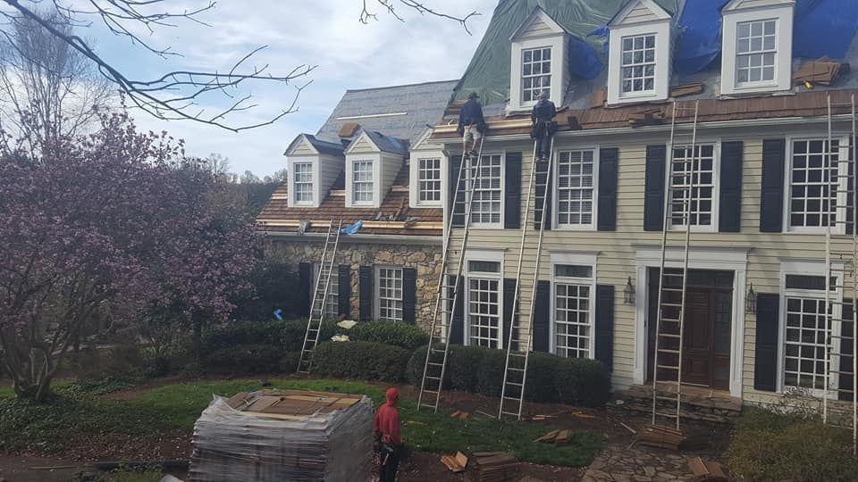 A group of people are working on the roof of a large house.