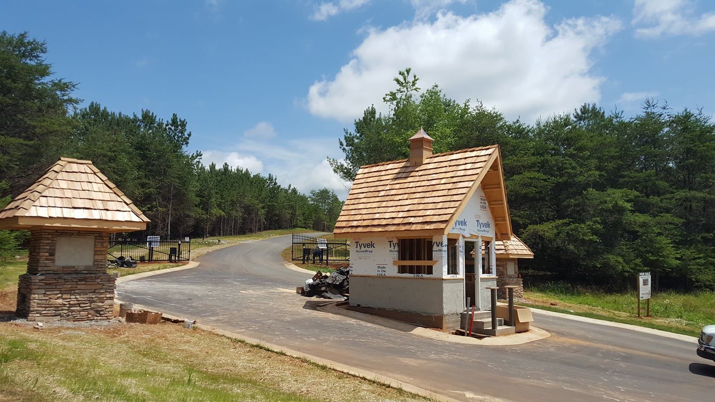 A small white building with a wooden roof is in the middle of a forest.