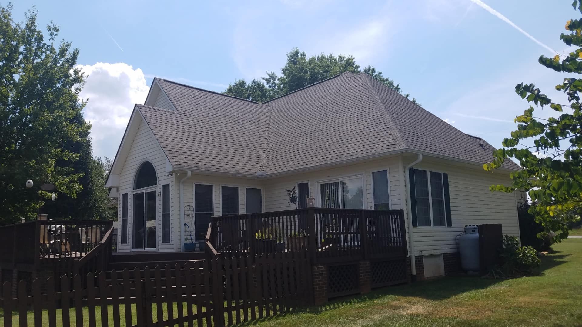 A large white house with a large deck and a fence in front of it.