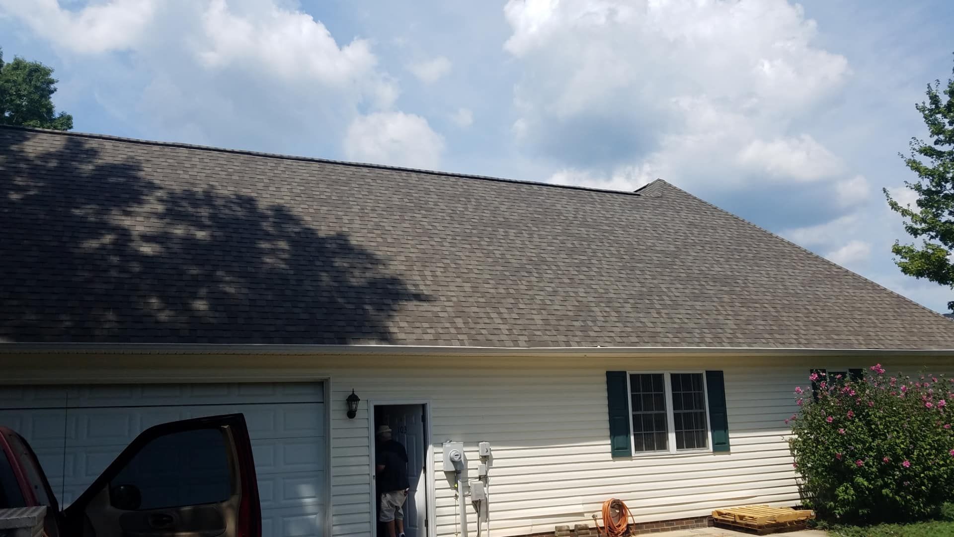 A white house with a gray roof and a car parked in front of it.