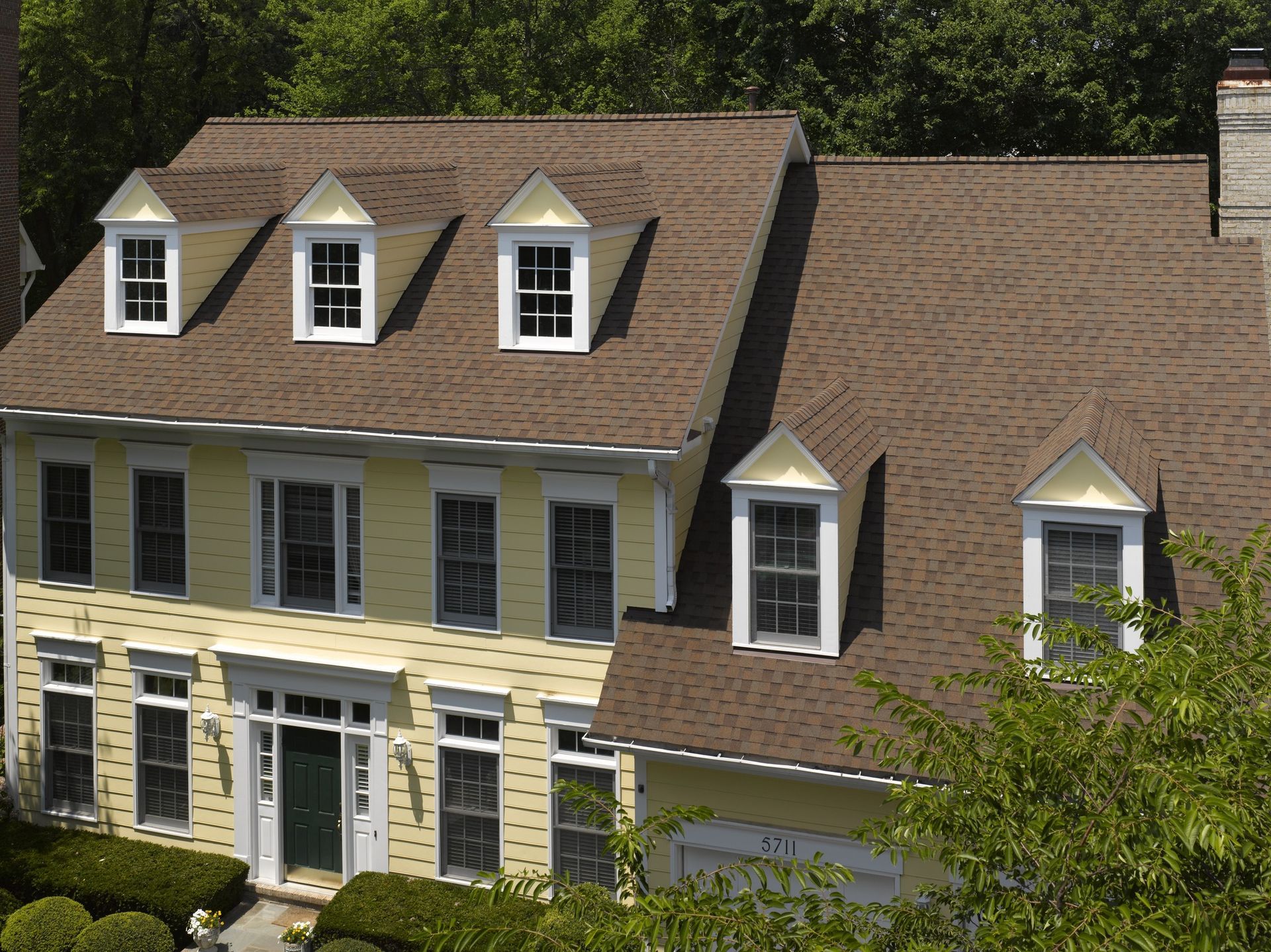 A large yellow house with a brown roof