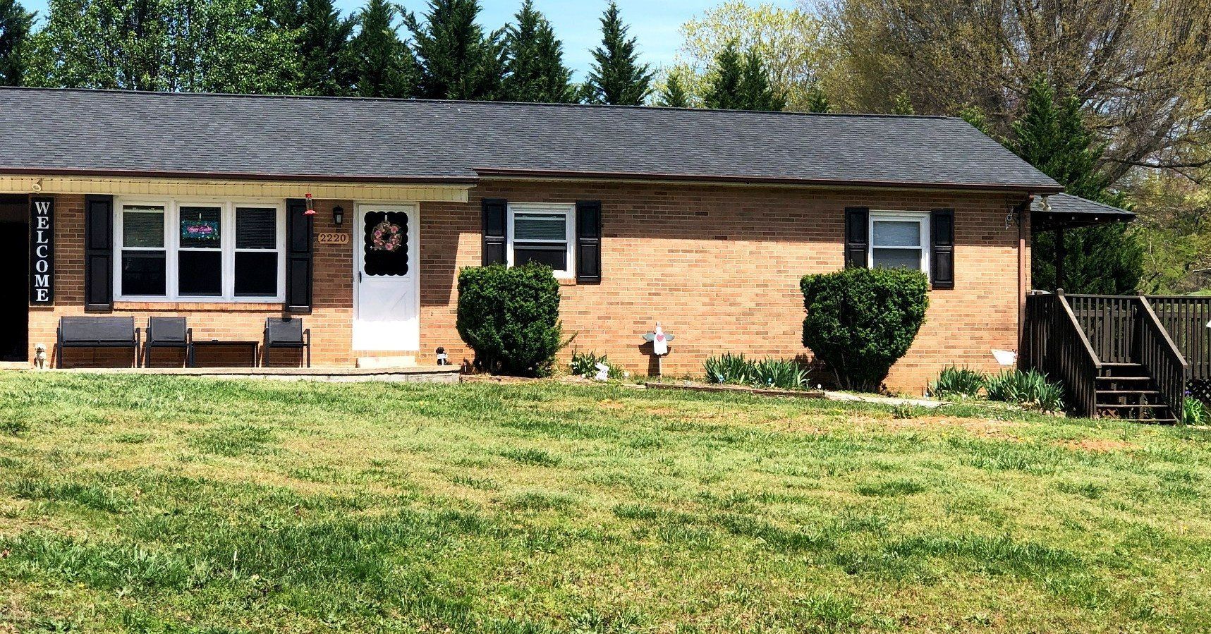 A brick house with a large lawn in front of it.