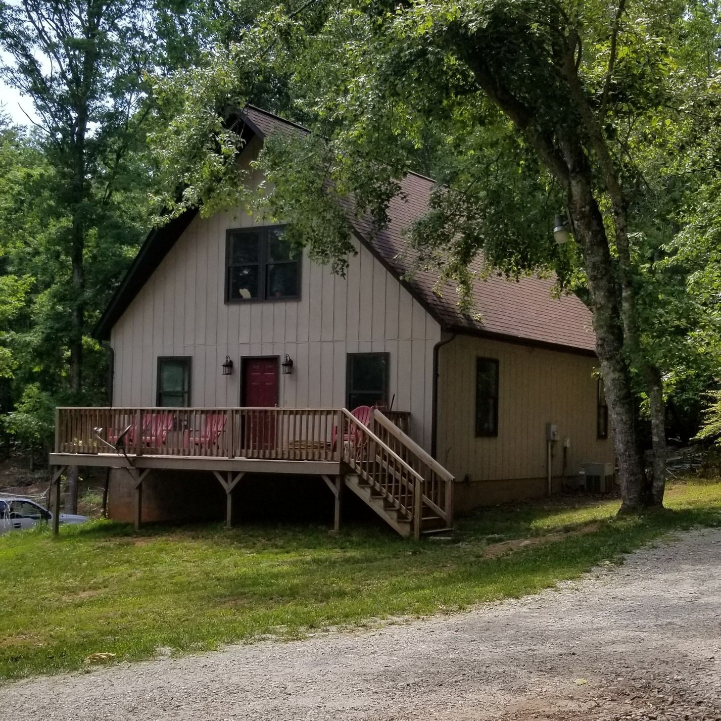 A house with a large deck and stairs surrounded by trees