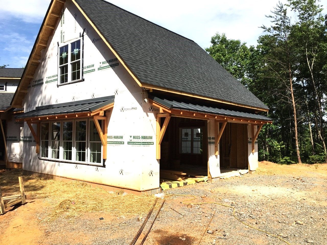 A white house with a black roof is being built.